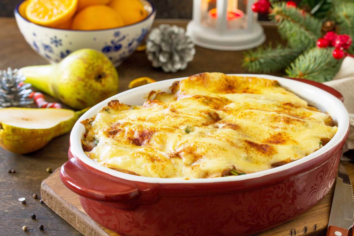 Kartoffelgratin mit Birne, Raclette-Käse und Speck auf einer festlichen Weihnachtstafel