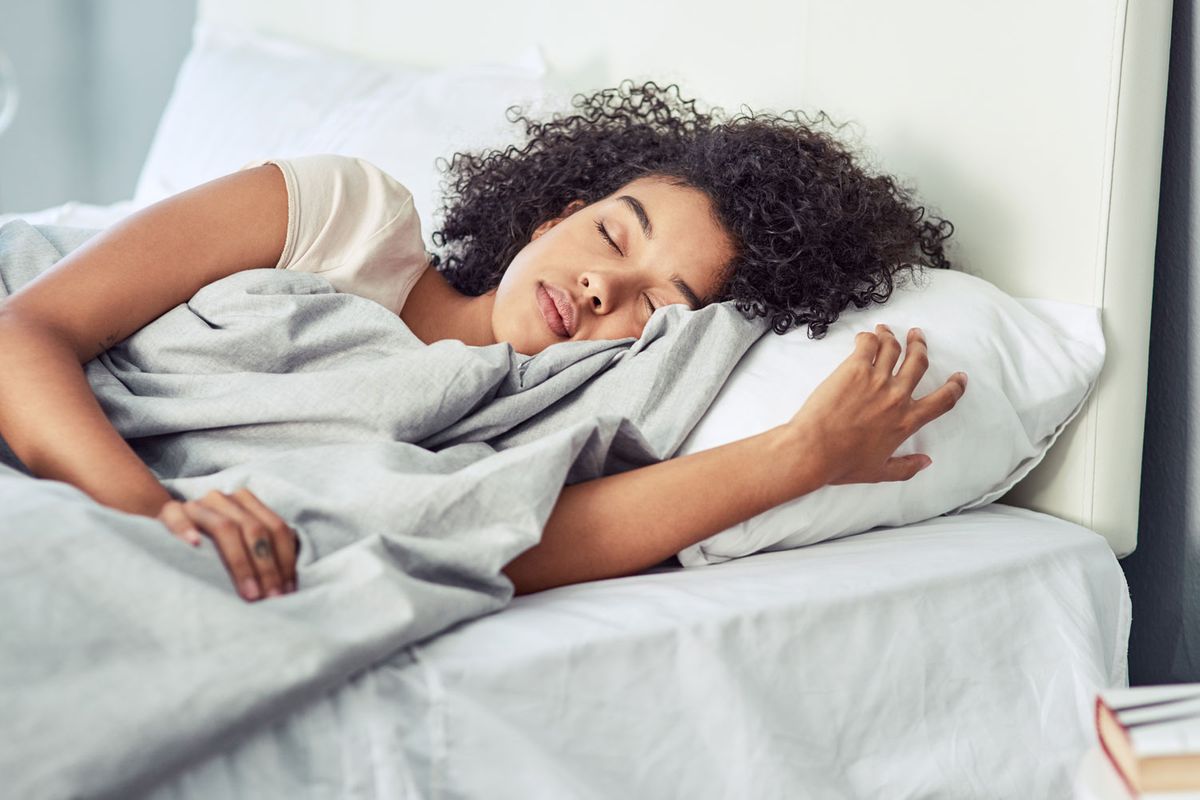 Frau liegt auf dem Bett auf einer Seite und schläft.