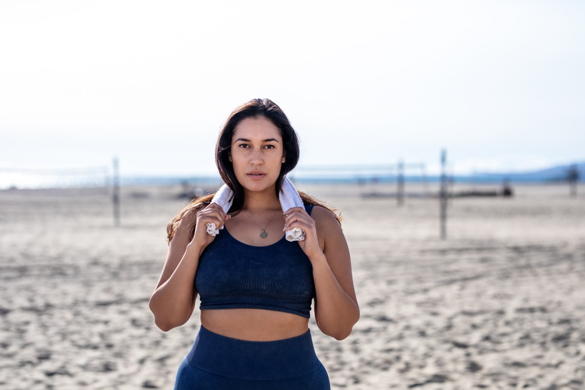 5 Kilo abnehmen: Dunkelhaarige Frau steht am Strand in Fitnessoutfit