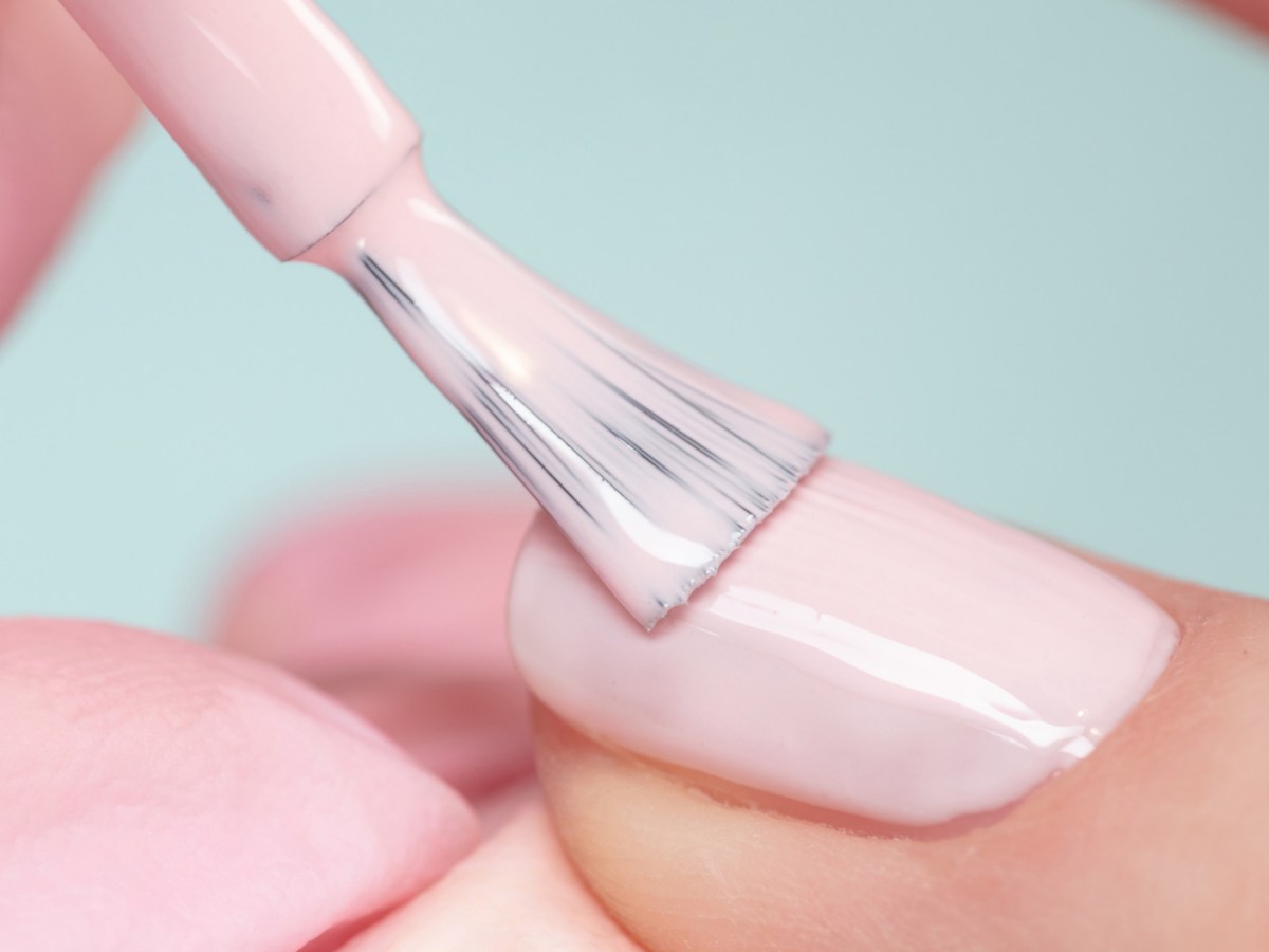 Person tr&auml;gt rosa farbenen Nagellack auf Nagel auf.
