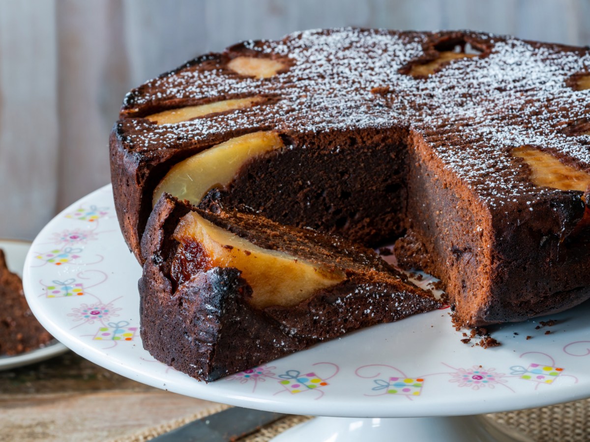 Schoko-Birnen-Kuchen auf weißer Servierplatte.