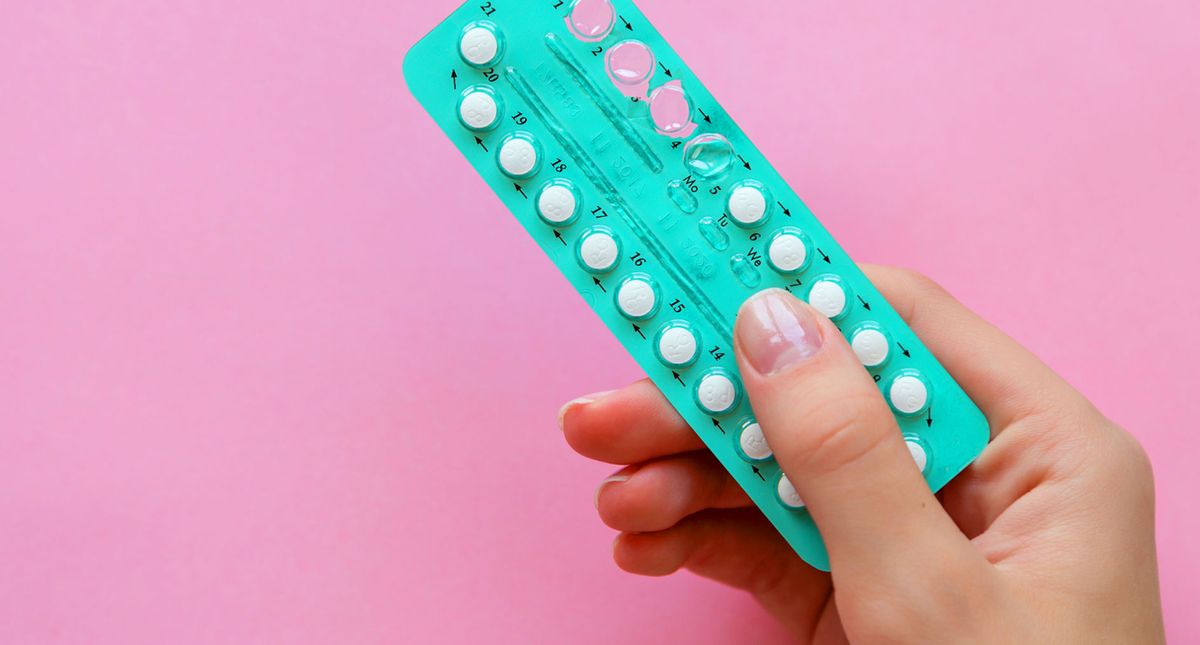 Weibliche hand h&auml;lt Pillenblister vor pinkem Hintergrund