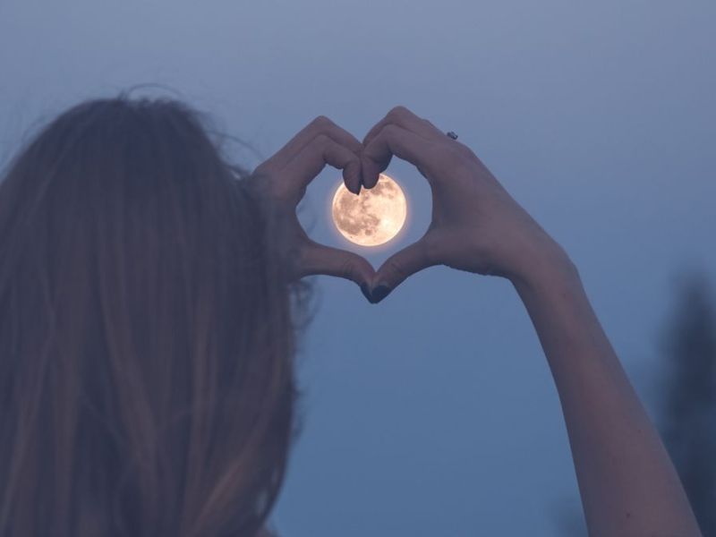 Person macht Liebeszeichen vor Vollmond