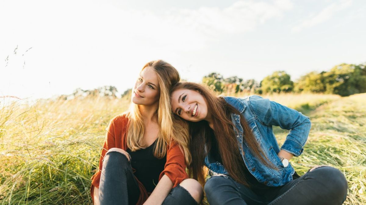 Zwei Freundinnen sitzen gemeinsam im Gras
