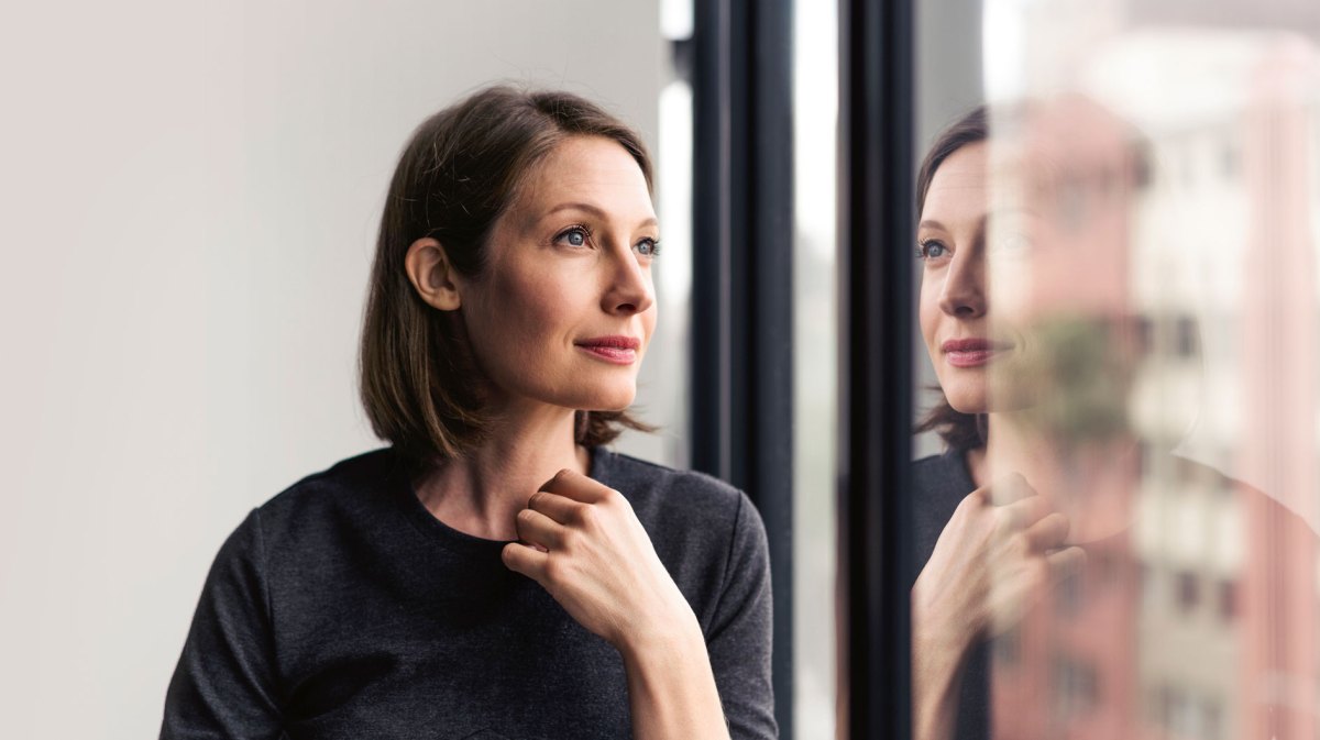 Frau schaut traurig aus dem Fenster