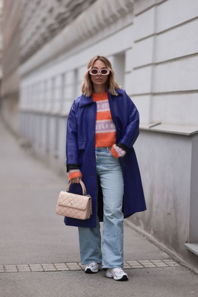 Influencerin Karin Teigl mit buntem Pullover und Chanel-Tasche.