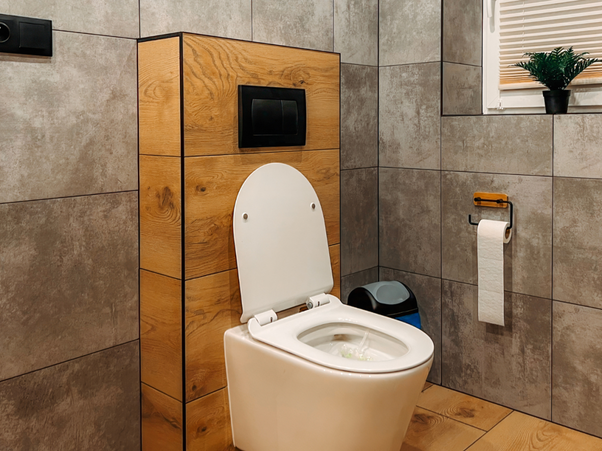 Ein Badezimmer mit grauen Fliesen und einer weißen Toilette.