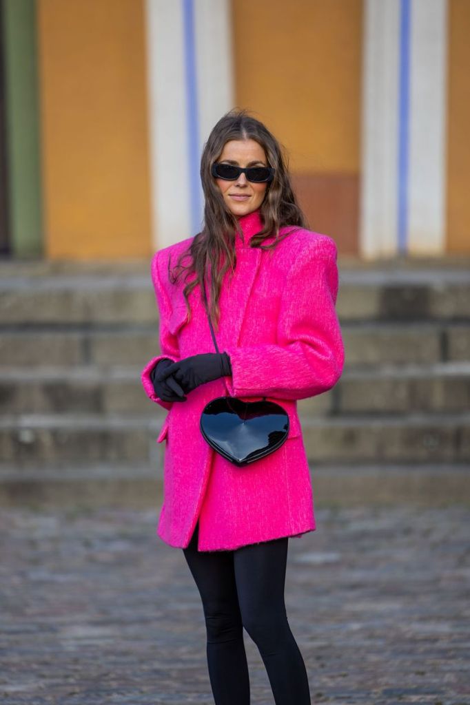 Influencerin Nina Sandbech kombiniert ihre pinke Jacke mit einer schwarzen Hose.