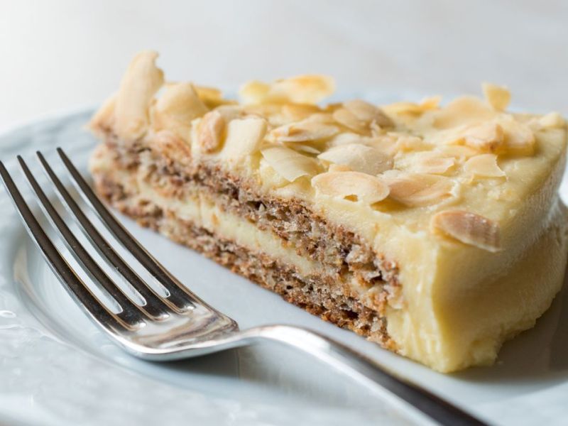 Schwedische Mandeltorte neben einer Gabel auf weißem Teller.