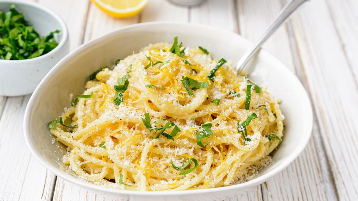 Weißer Teller mit Spaghetti, Zitronenabrieb und Parmesan.