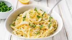 Wei&szlig;er Teller mit Spaghetti, Zitronenabrieb und Parmesan.