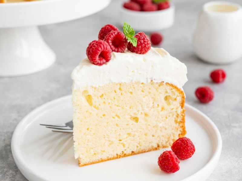 Heller Milchkuchen auf einem weißen Teller mit frischen Himbeeren.