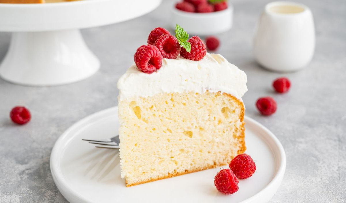 Heller Milchkuchen auf einem weißen Teller mit frischen Himbeeren.