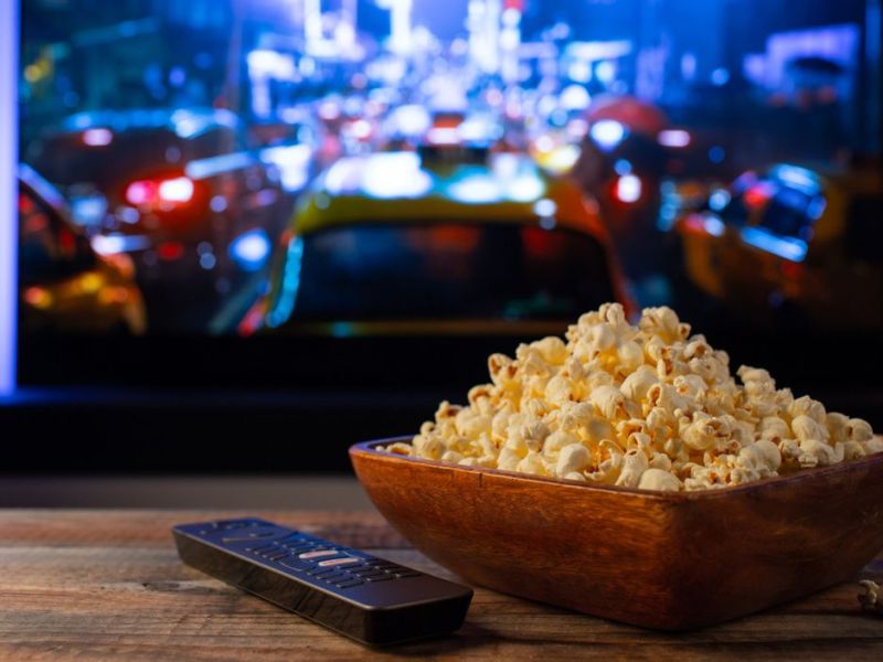 Fernseher mit Fernbedingung und Popcorn auf dem Tisch