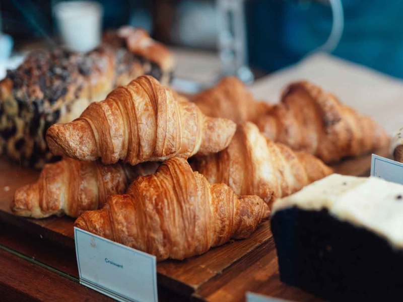 Backwaren einer Bäckerei. Im Vordergrund liegen Croissants.