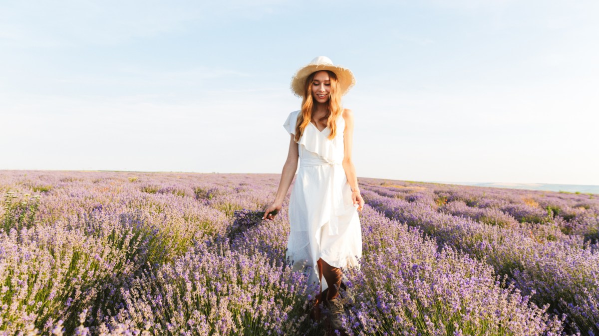 Frau in weißem Kleid, die in einem Lavendelfeld steht