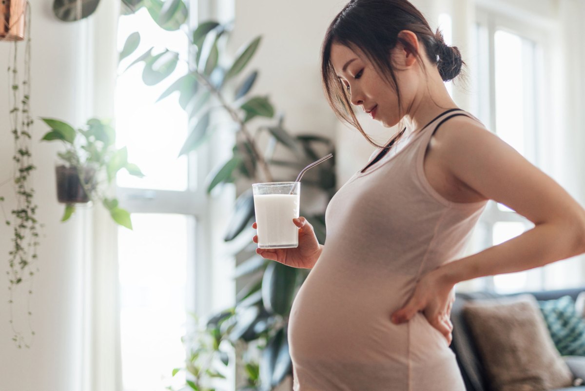 Schwangere Frau mit Milchglas in der Hand
