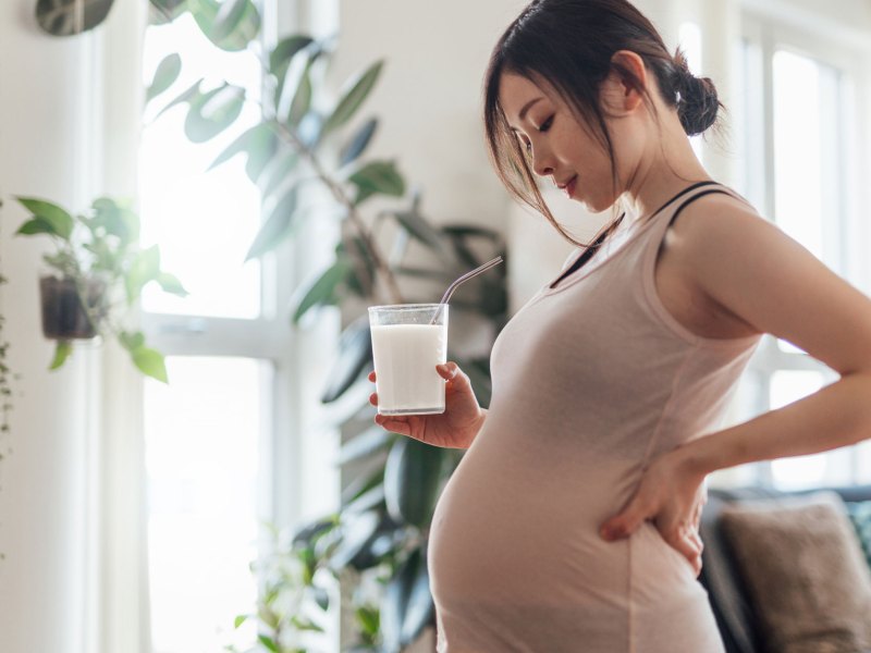 Schwangere Frau mit Milchglas in der Hand