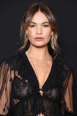 Lily James trägt einen locker gesteckten Zopf mit Curtain Bangs: Die langen Strähnen rahmen das Gesicht perfekt ein.