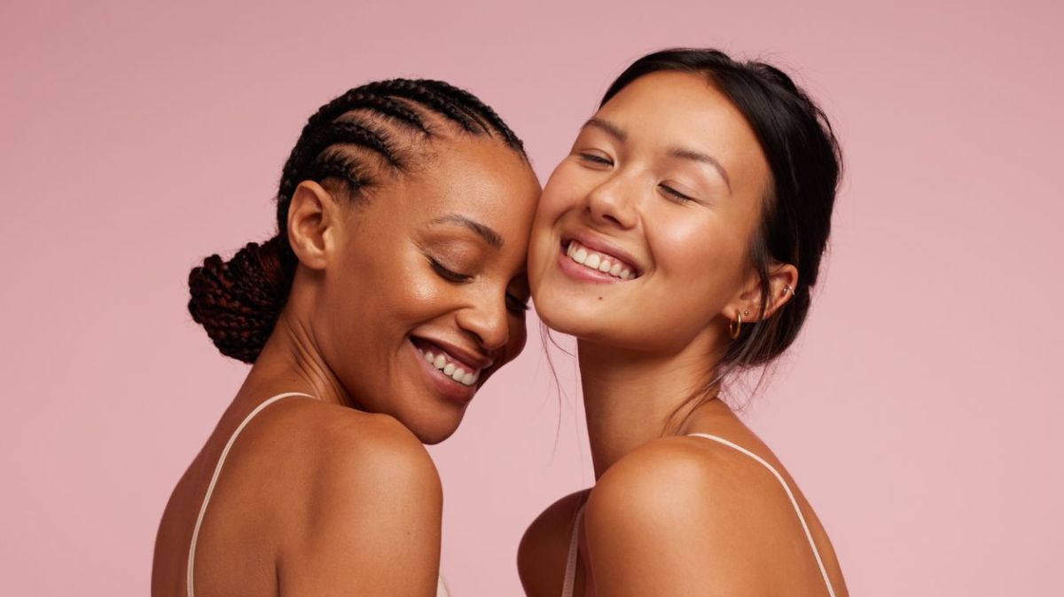 Zwei Frauen am Lachen vor rosafarbenen Hintergrund