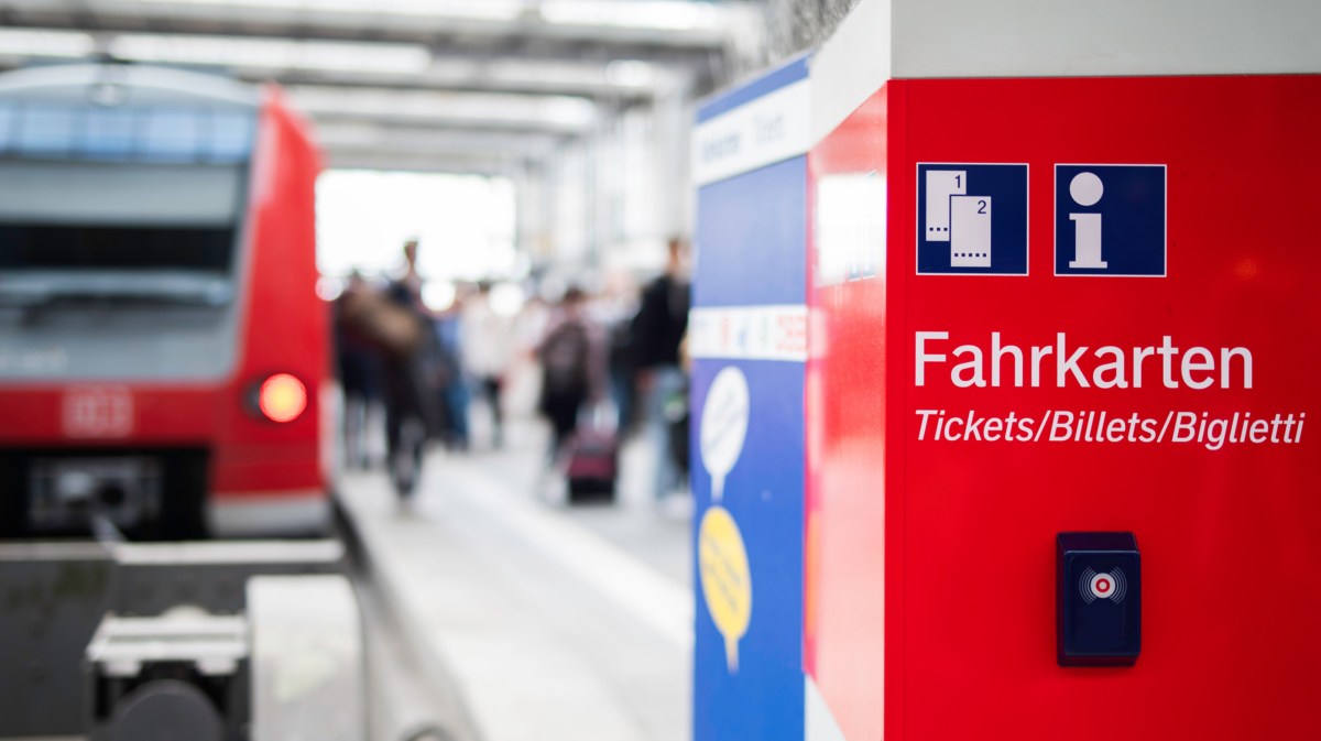 Fahrkartenautomat mit Bahn im Hintergrund