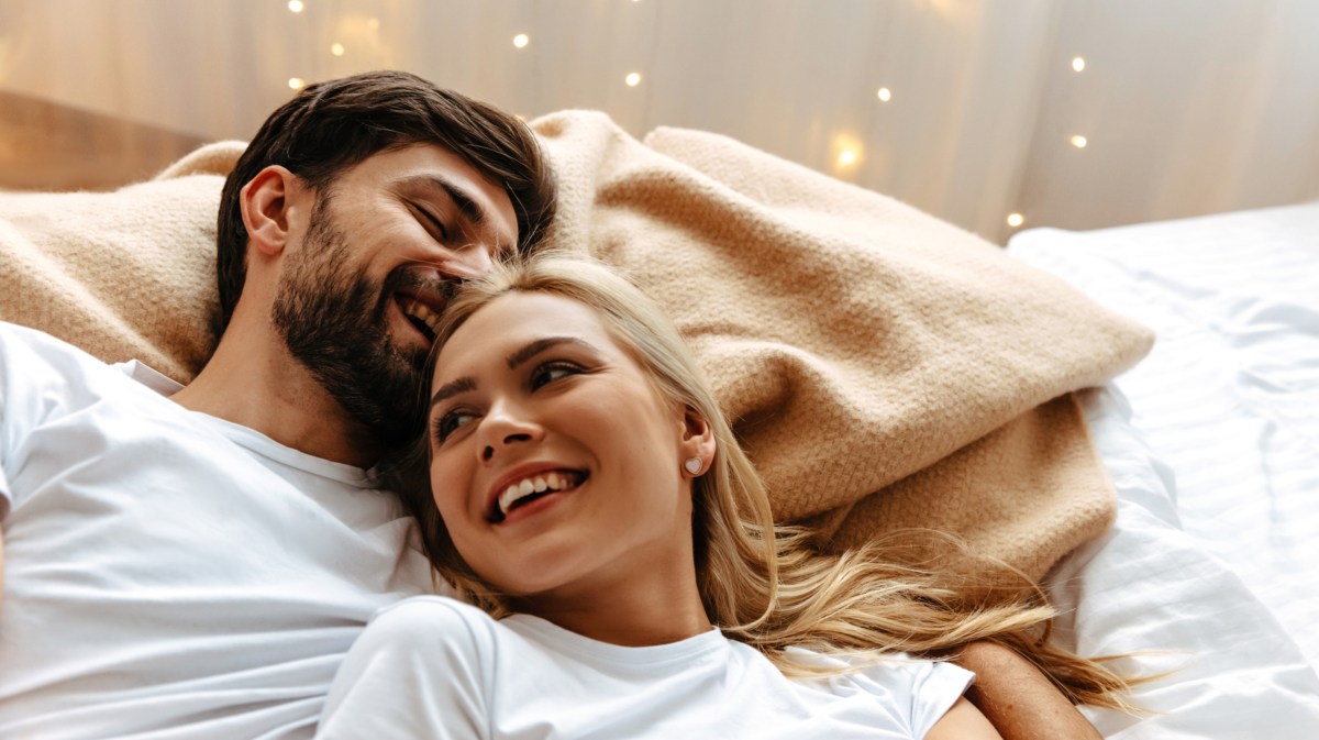 Frau und Mann kuscheln lachend im Bett