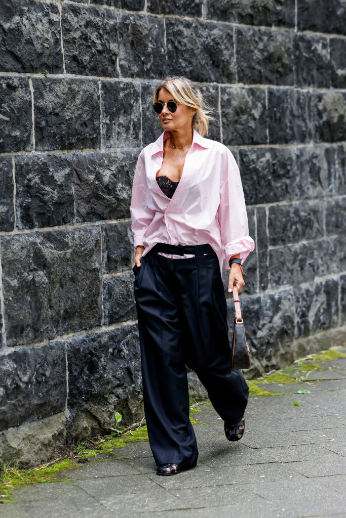 Gitta Banko trägt ein Oversize-Hemd und eine schwarze Stoffhose.