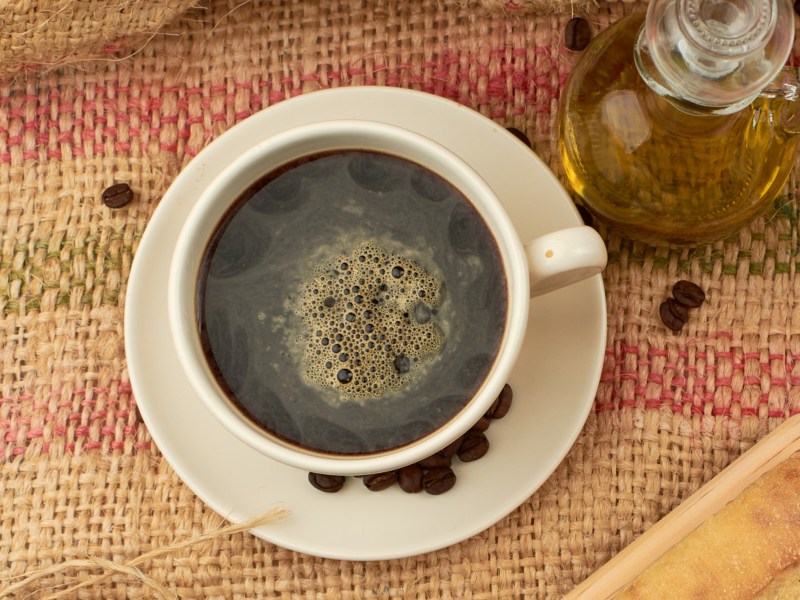 Kaffeetasse und Karaffe mit Olivenöl stehen auf einem Tisch