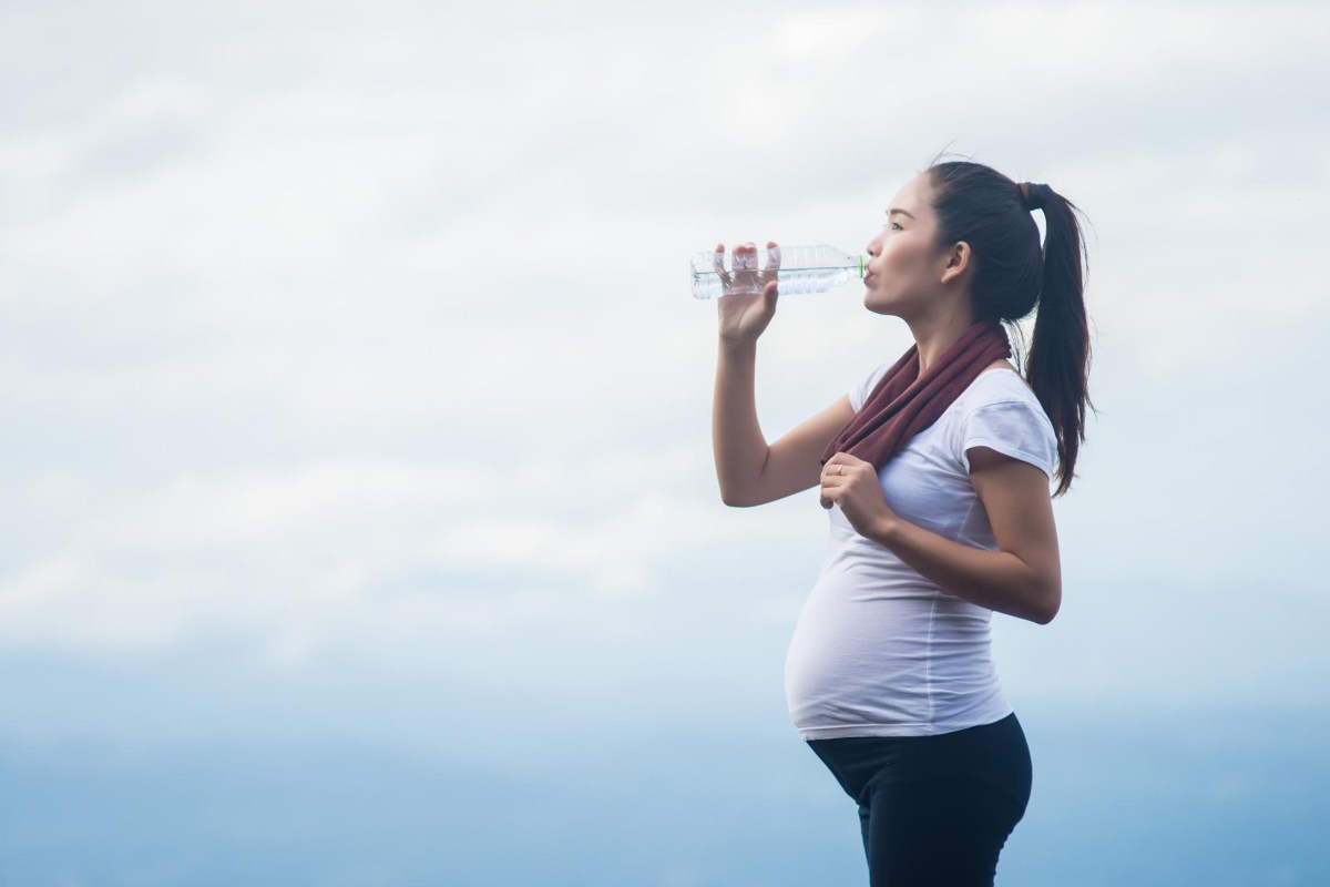 Schwangere Frau trink aus einer Wasserflasche