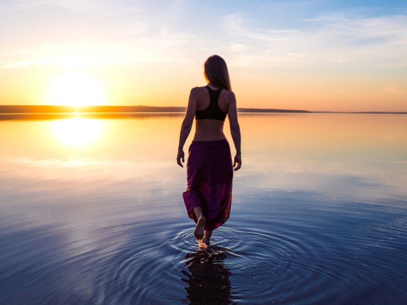 Frau steht mit langem Kleid im Wasser