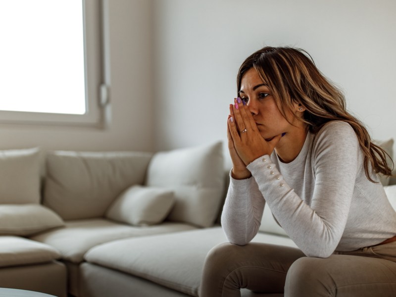 Frau sitzt nachdenklich auf Sofa