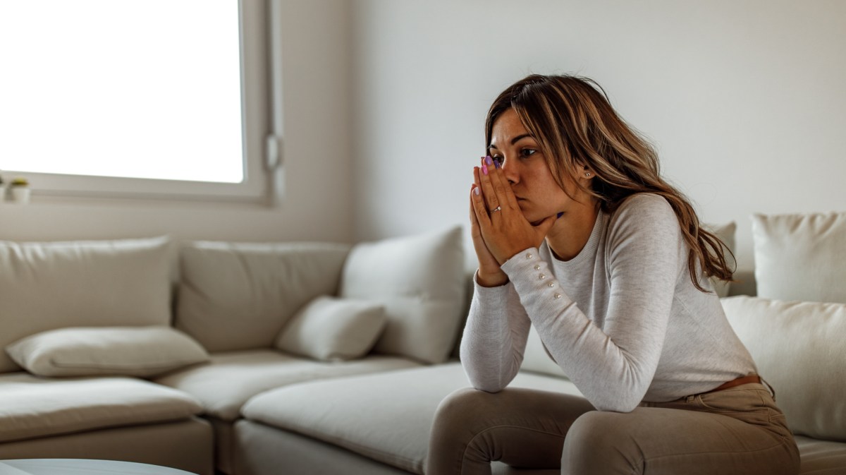 Frau sitzt nachdenklich auf Sofa