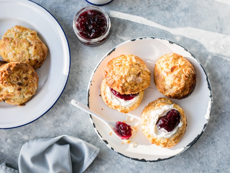 Scones mit Clotted Cream und Marmelade auf Teller.