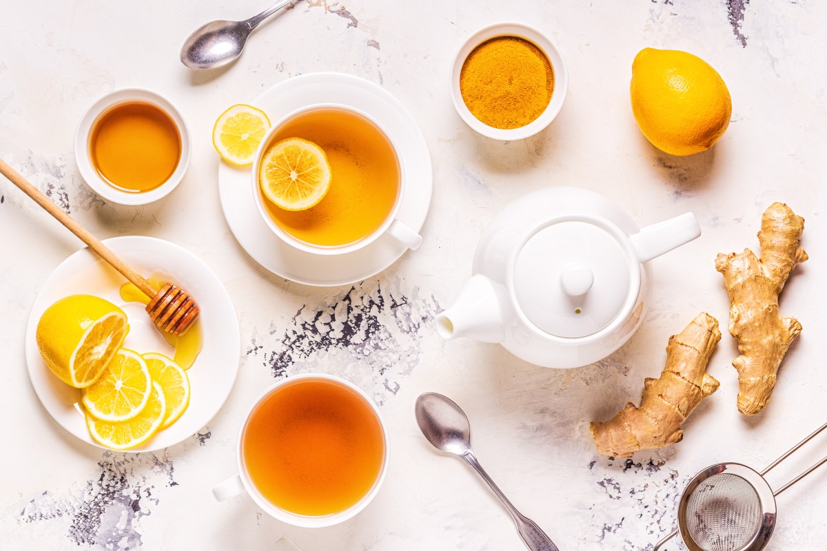 Hausmittel gegen Schleim im Hals wie Tee, Zitrone, Honig und Ingwer auf einem hellen Untergrund