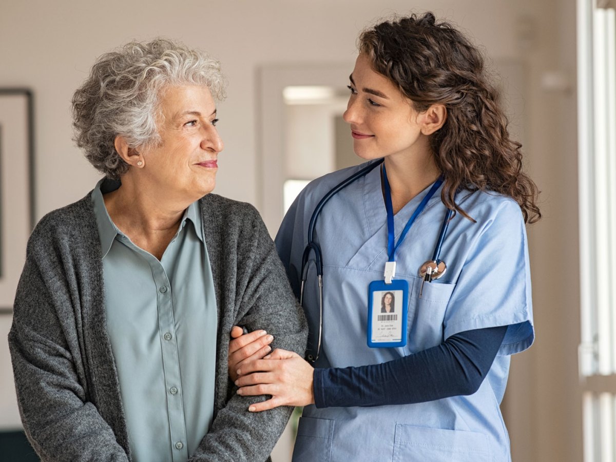 Pflegerin h&auml;lt den Arm einer &auml;lteren Frau