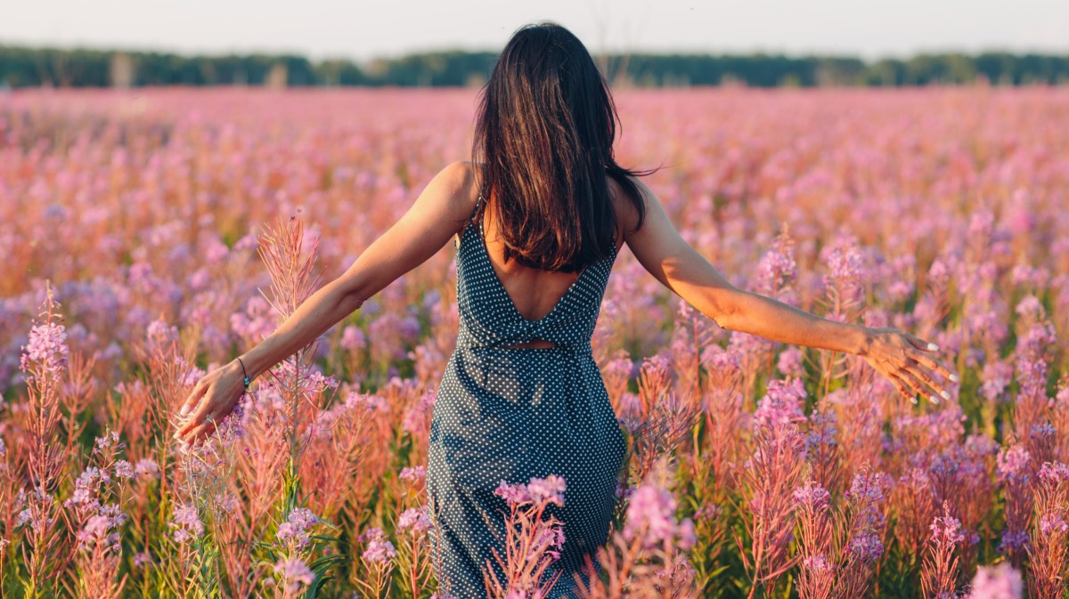 Frau läuft durch Blumenfeld