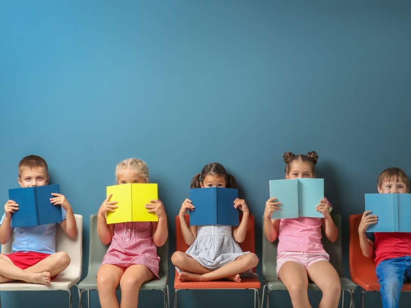 Kinder mit Büchern vor blauer Wand