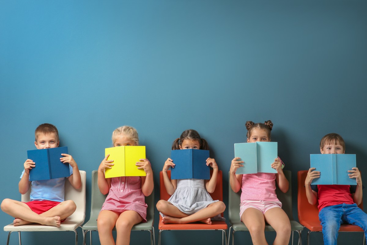 Kinder mit Büchern vor blauer Wand