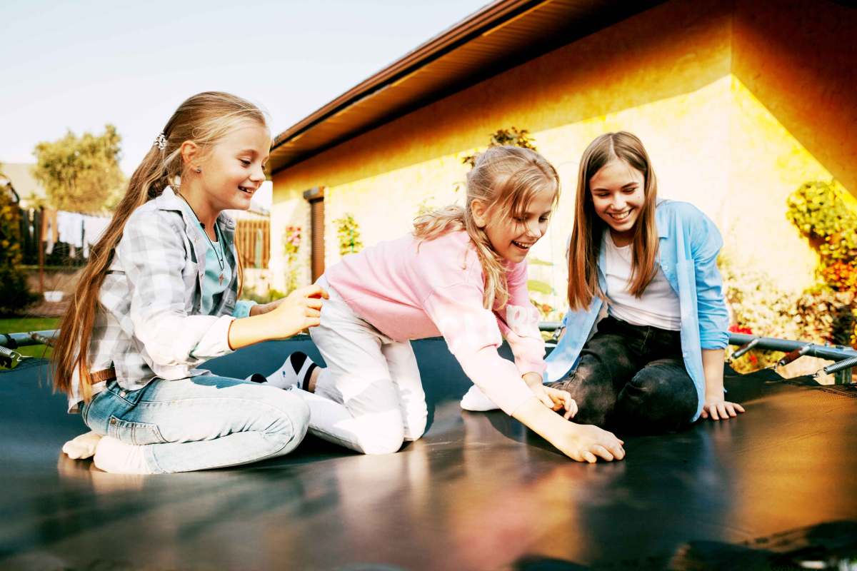 Drei Mädchen auf einem Trampolin, das ganz in der Nähe ihres Wohnhauses steht.