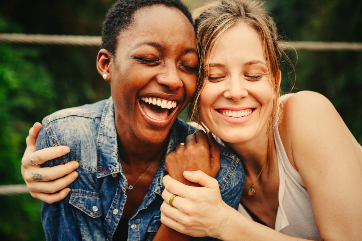 Zwei Frauen sitzen glücklich nebeneinander und halten sich im Arm