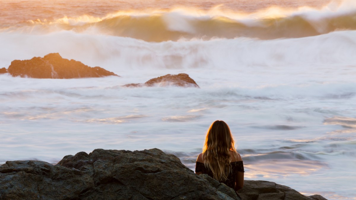 Frau sitzt nachdenklich am Meer