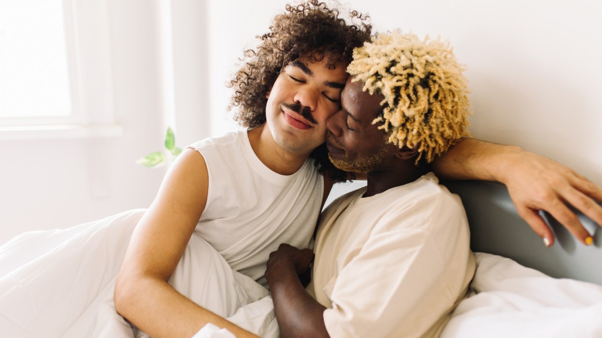 Schwules Paar, das sich liebevoll im Bett umarmt