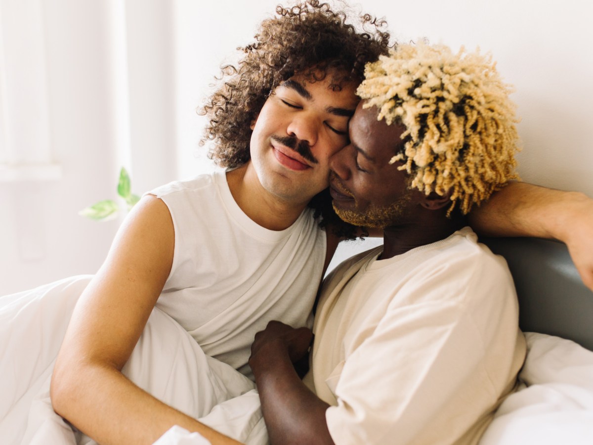 Schwules Paar, das sich liebevoll im Bett umarmt