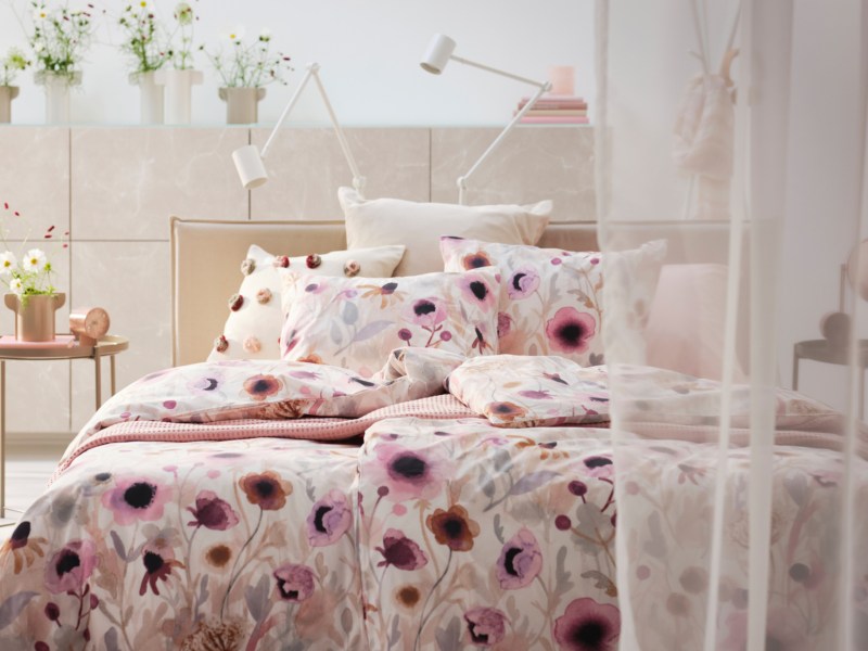Hell eingerichtetes Schlafzimmer mit bunter Blumen-Bettwäsche
