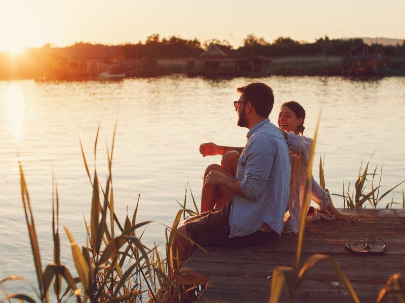 Frau und Mann am Steg am Lachen im Sonnenuntergang