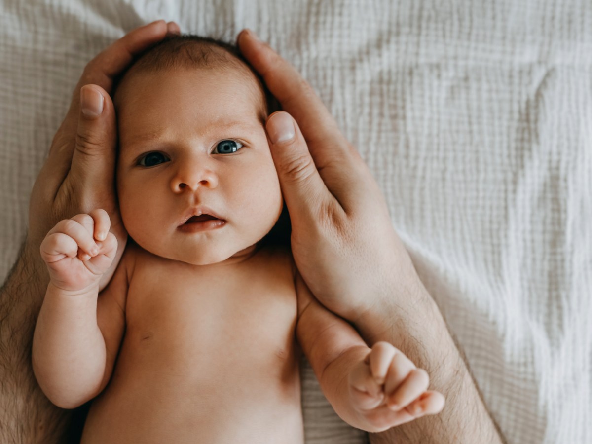 Babykopf in Hand von Erwachsenen