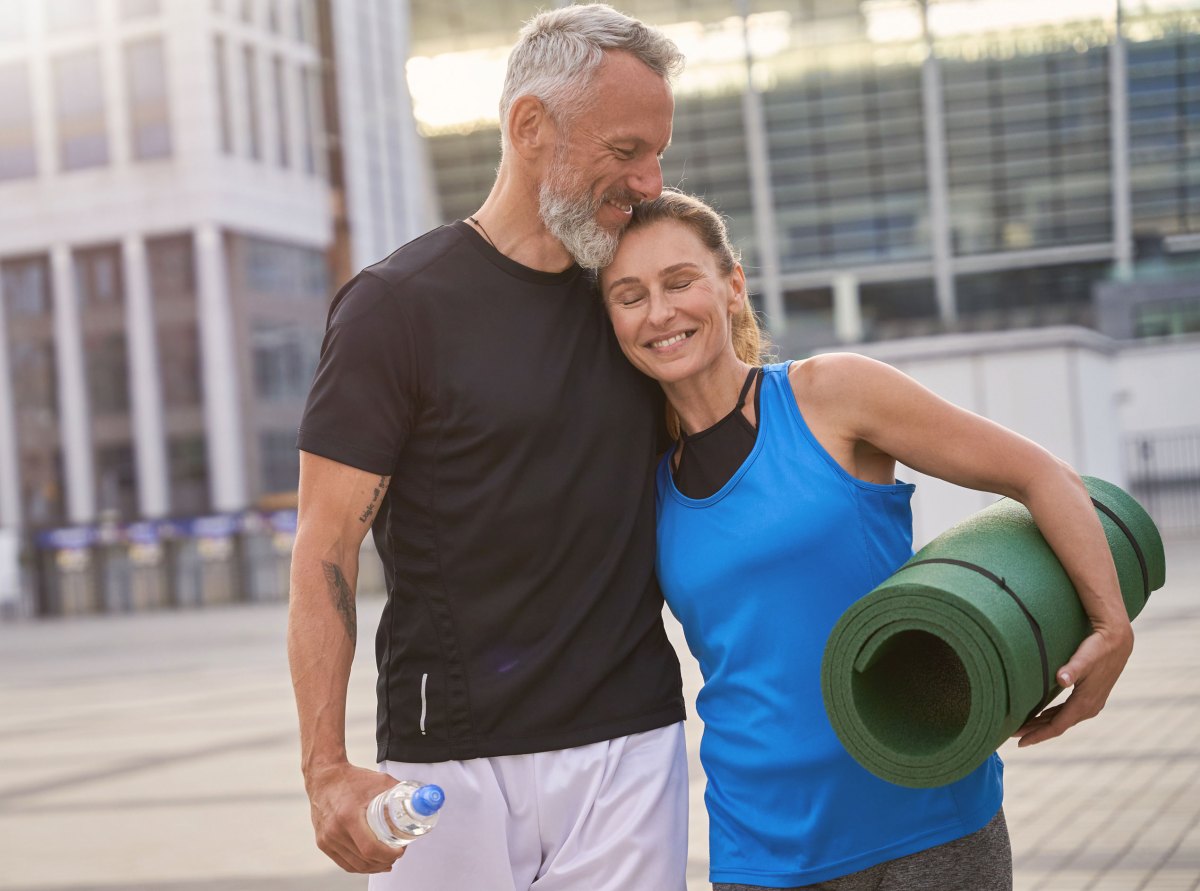 Porträt eines hübschen reifen Paares, Mann und Frau in Sportkleidung, die nach dem morgendlichen Training gemeinsam in der Stadt spazieren gehen