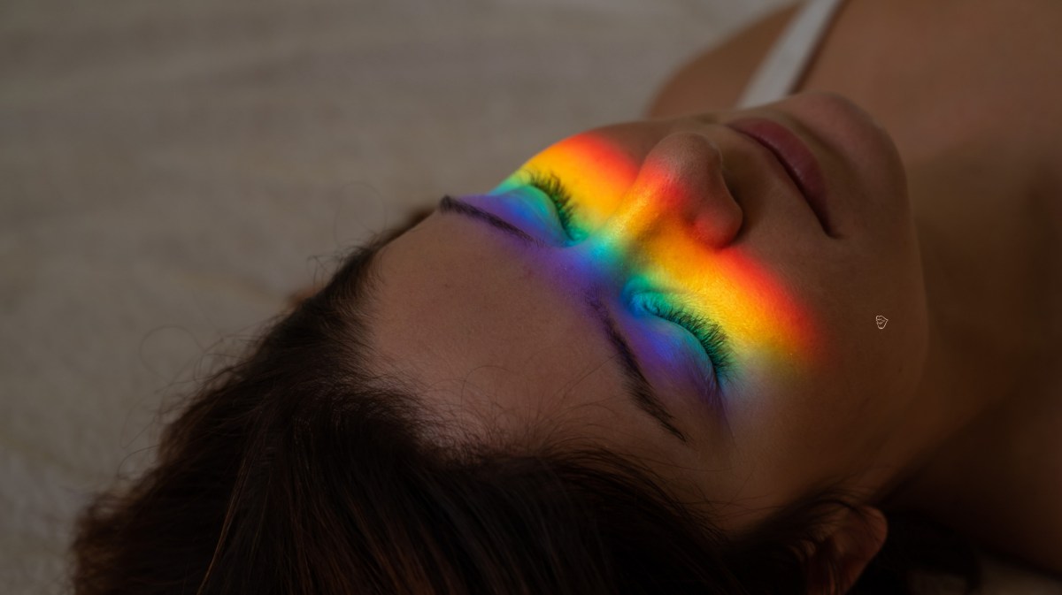 Frau, die auf dem Boden liegt und einen Regenbogen im Gesicht hat.