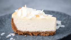 Käsekuchen mit Kokosraspeln auf einem blauen Teller.