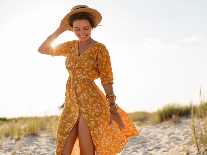 Frau in orangem Kleid am Strand.